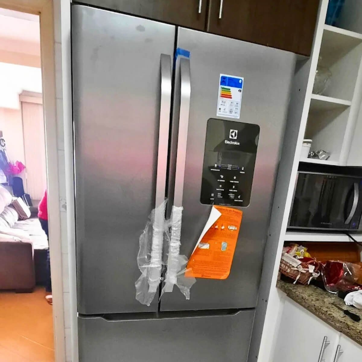 Refrigerador Electrolux Inox Frost Free sendo avaliado por técnico especializado para troca de componentes.