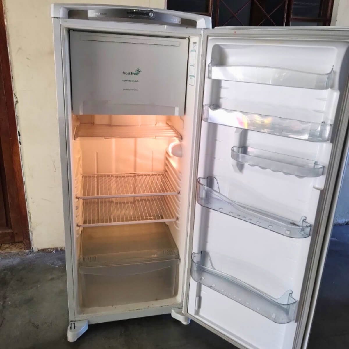 Interior de geladeira doméstica aberto e com iluminação funcionando após manutenção realizada pela Veralice Refrigeração em Curitiba.