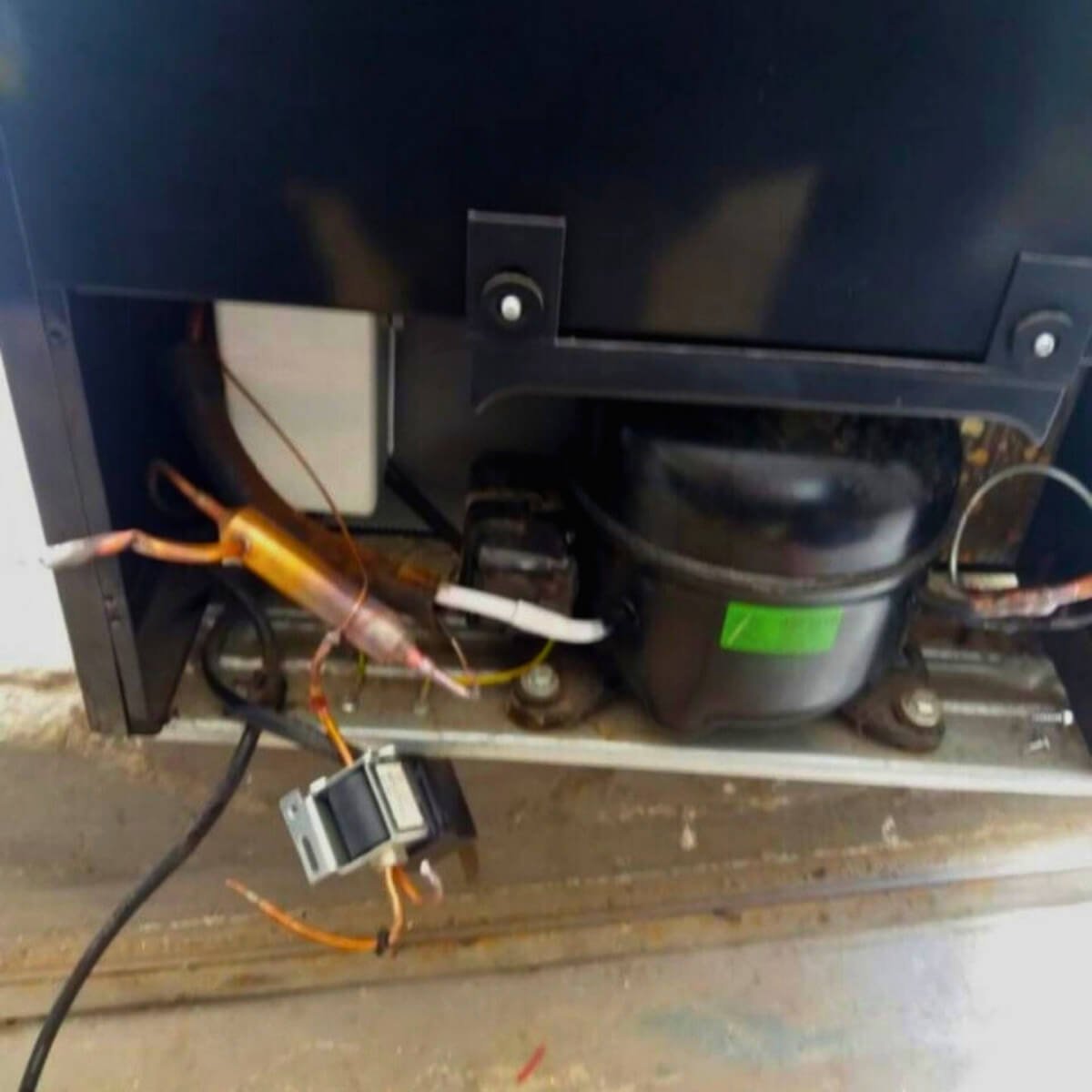 Manutenção técnica no compressor (motor) e troca de filtro secador na parte traseira de geladeira.