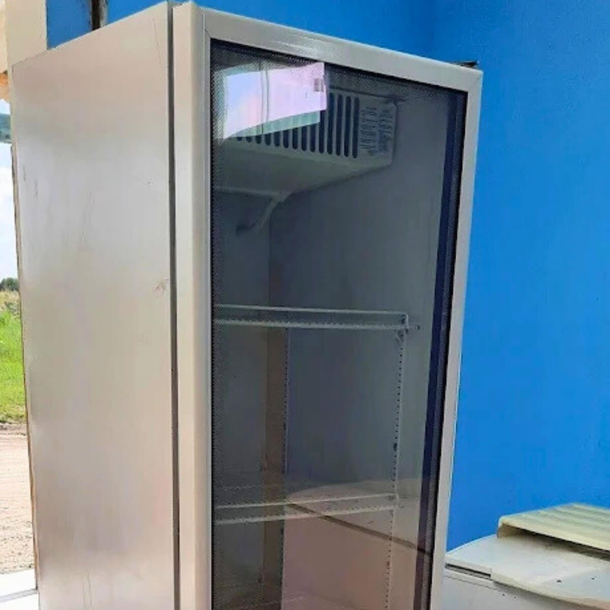 Geladeira expositora vertical branca vazia e limpa após serviço de higienização e troca de borrachas.