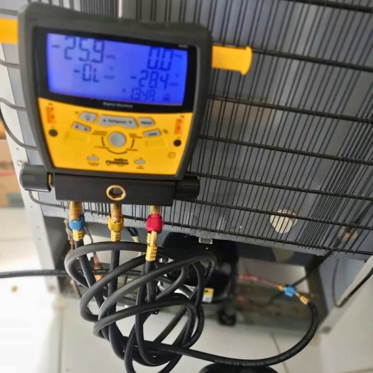 Uso de manifold digital para recarga de gás e diagnóstico de precisão em geladeira por técnico da Veralice em Curitiba.